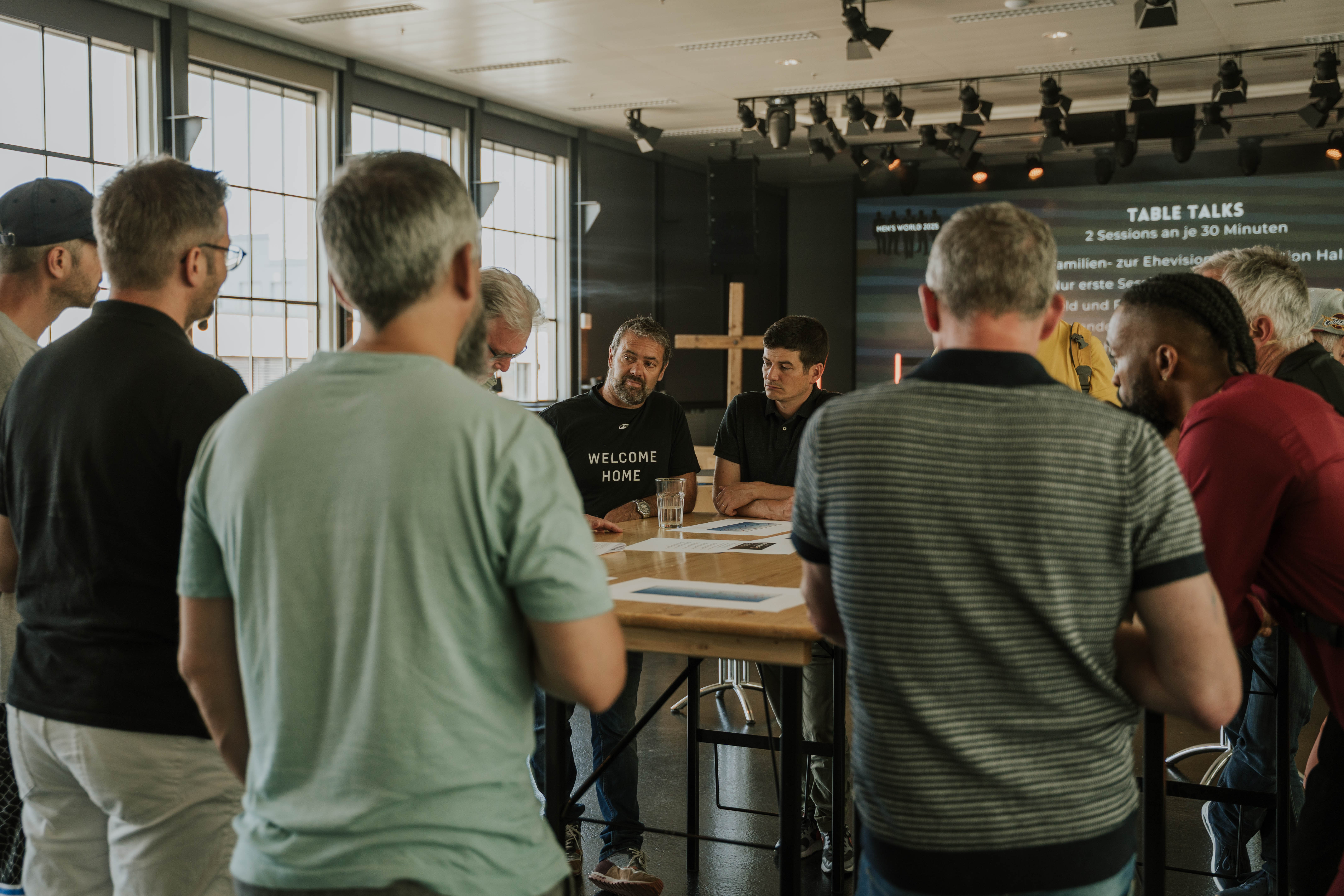 Mens standing around a table and talking